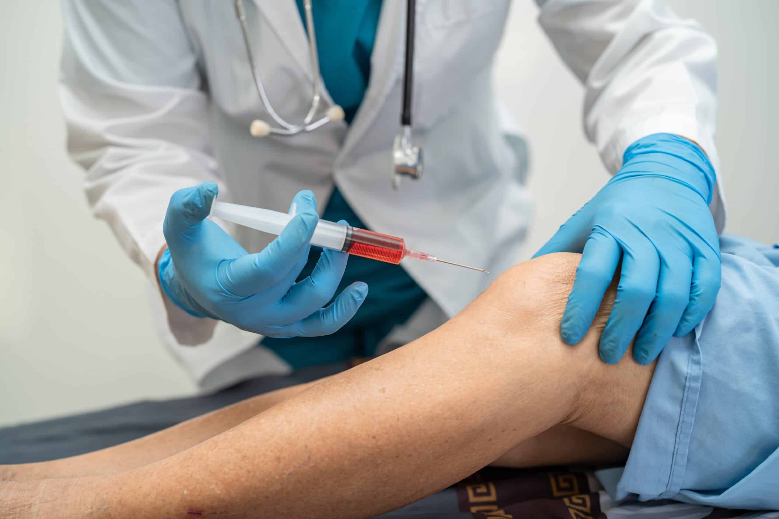 Close up of a doctor administering PRP injections into a patient's knee for chronic joint pain relief