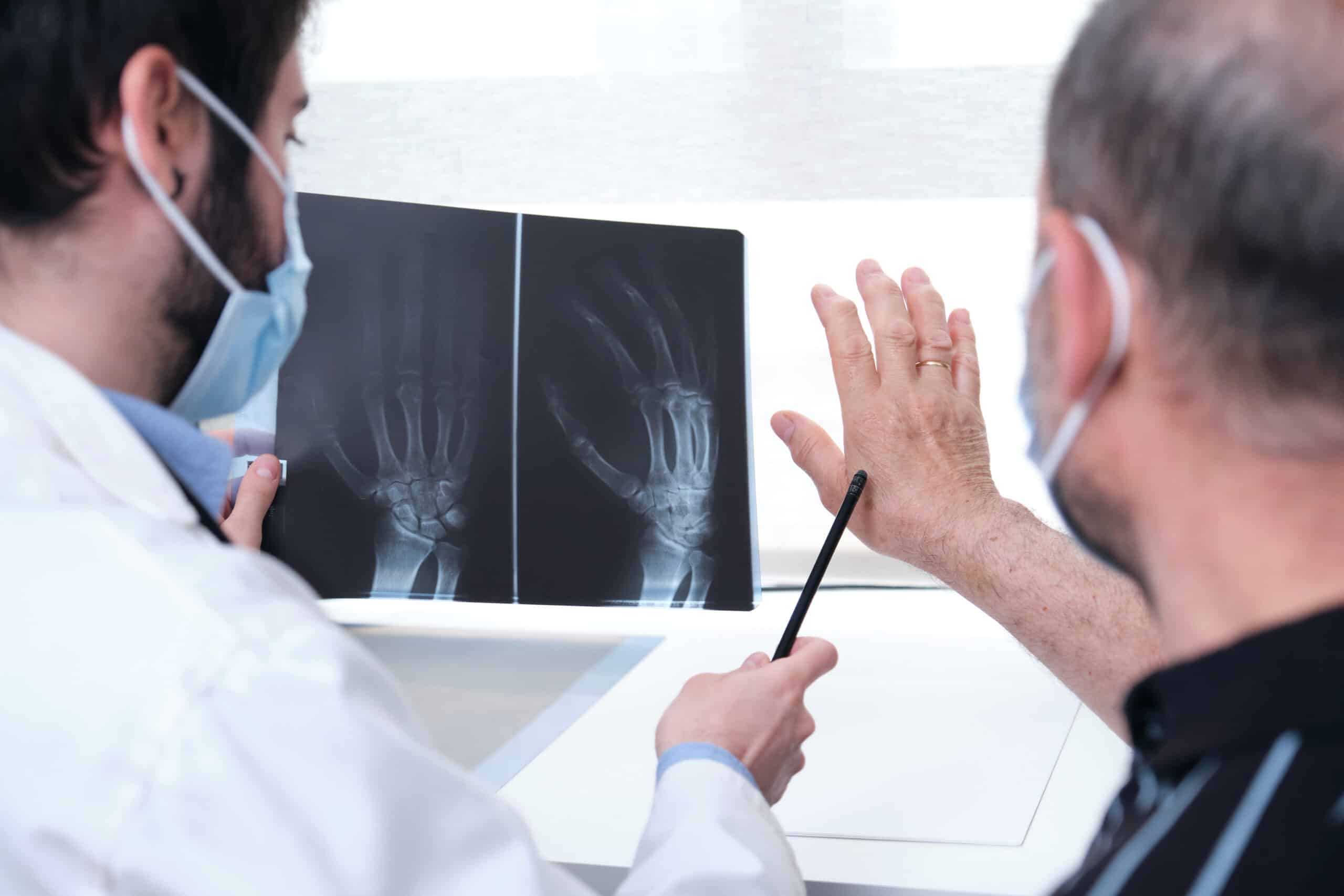 Doctor and patient looking over some scans of the patient's hand for the source of his chronic pain