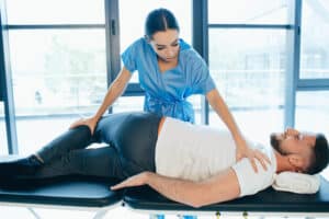 Man laying on treatment table being treated by a female provider to relieve lower back pain.