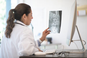 Doctor examining an x-ray of a patient's spine before vertebral augmentation to relieve compression fracture pain.