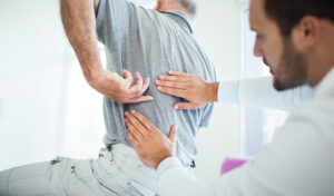 Older male patient pointing to the spot that hurts during a doctor's appointment.